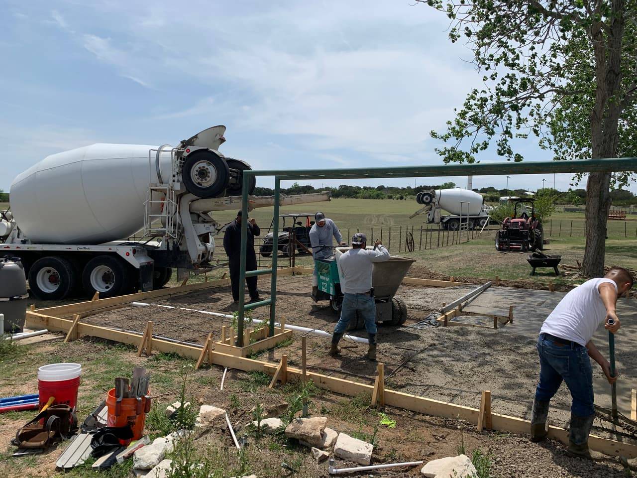 Crew finishing a round concrete foundation pad at dusk with a concrete truck on site