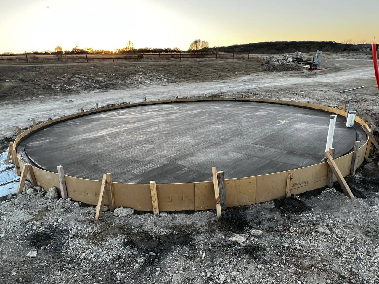 Crew finishing a large reinforced concrete pad pour with a concrete pump truck in the Highland Lakes area