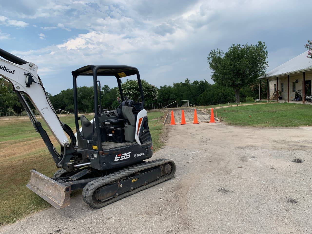 Mini excavator parked on a freshly graded rural site ahead of a concrete pour in the Highland Lakes area