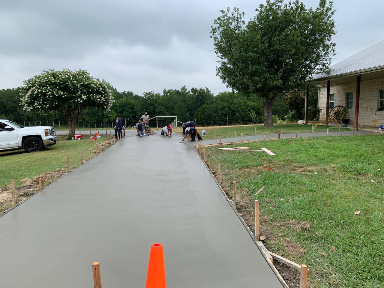 Crew finishing a new concrete driveway pour near a rural Highland Lakes home
