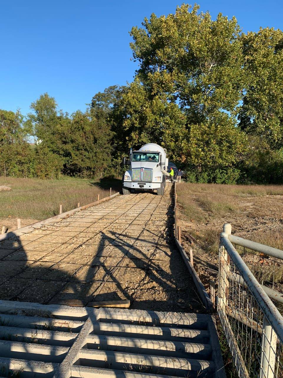 Concrete mixer truck pouring a new driveway on a wooded rural Highland Lakes lot