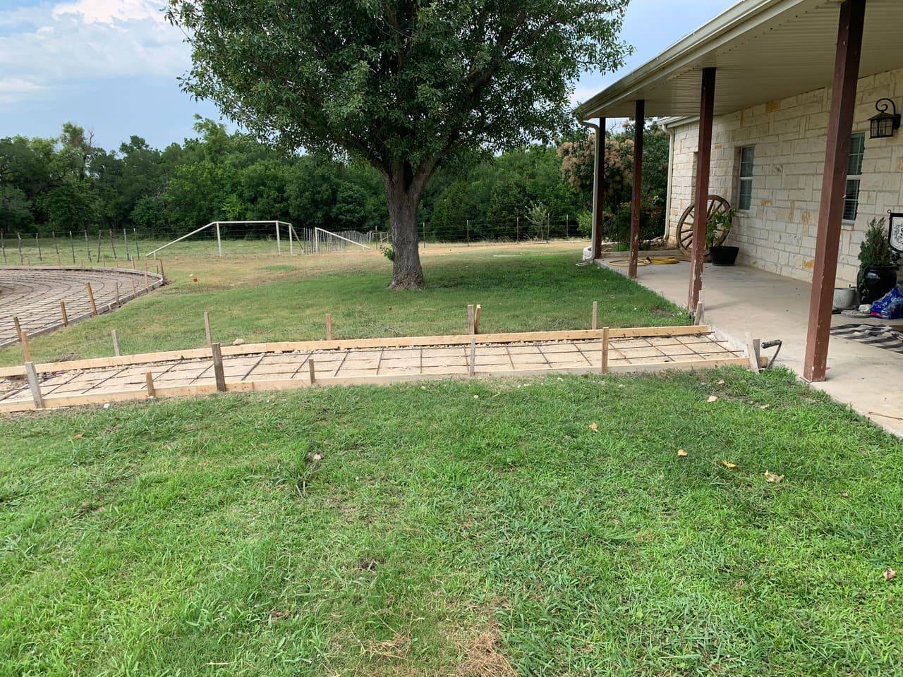 Rebar-reinforced forms set for a concrete walkway pour beside a stone ranch home