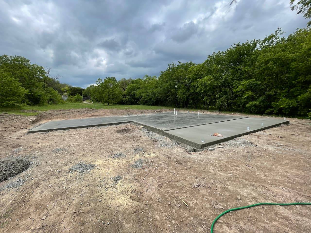 Aerial view of a poured concrete foundation slab with anchor bolt sleeves set for framing