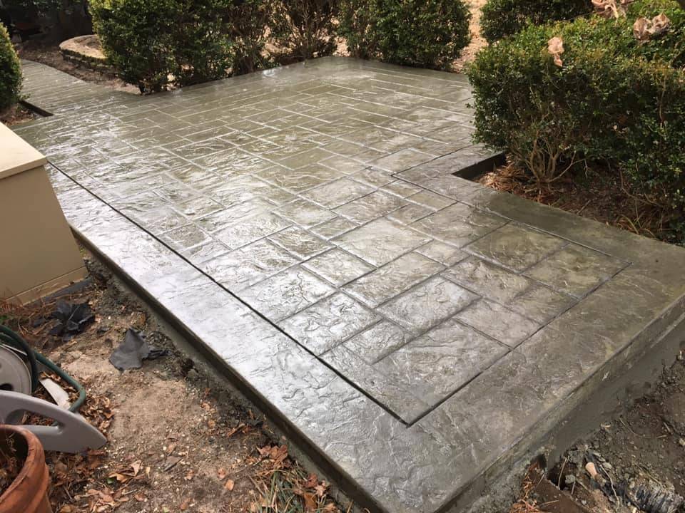 Stamped concrete patio and walkway finished in an ashlar stone pattern beside a home