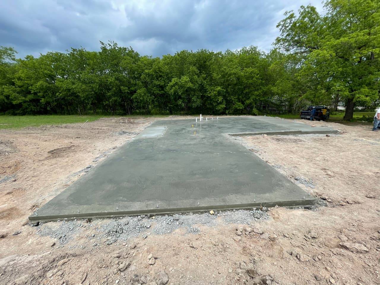 Finished rectangular concrete foundation slab poured and ready for framing on a rural lot