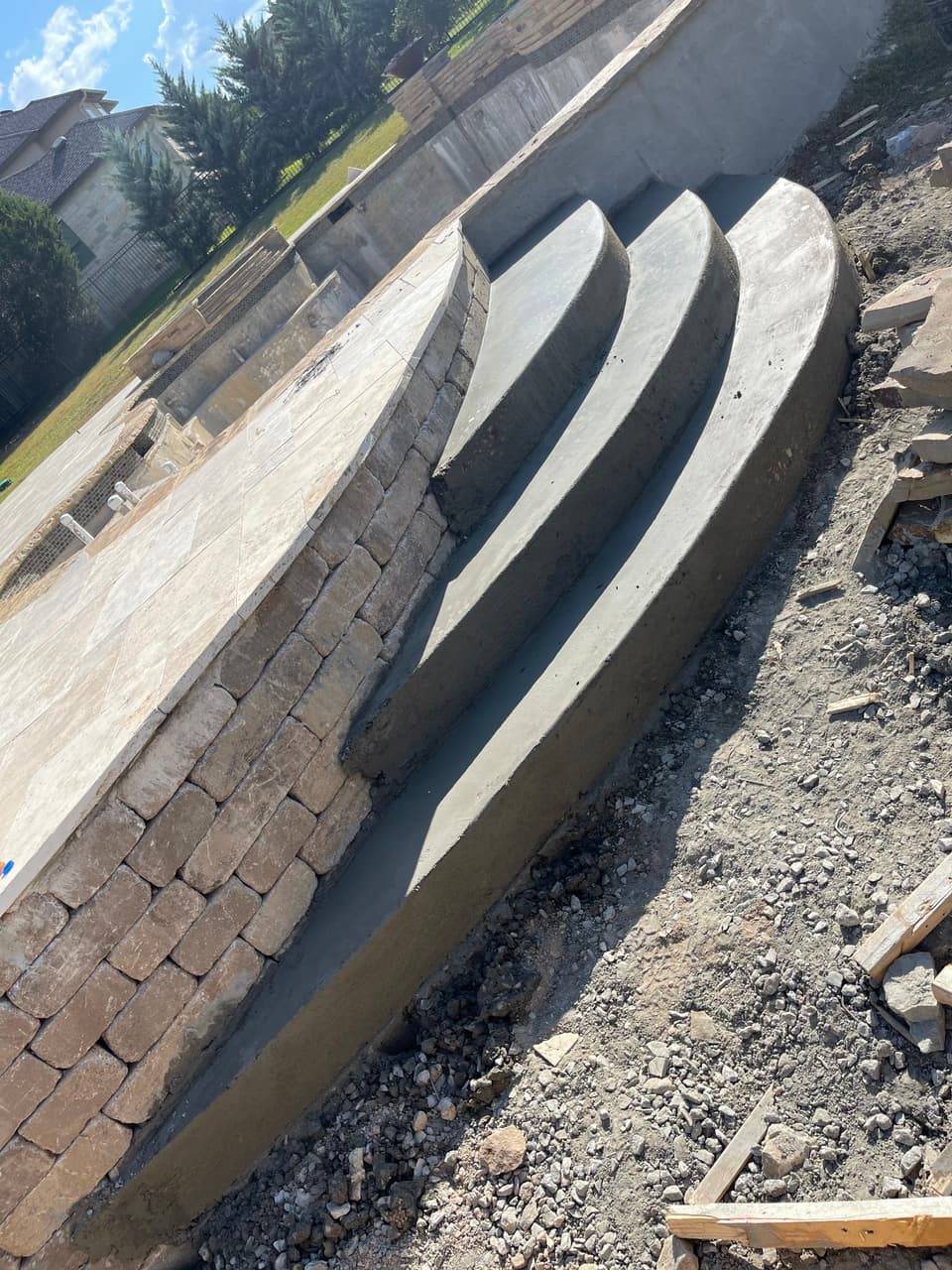 Finished concrete pool deck steps built into a stone retaining wall